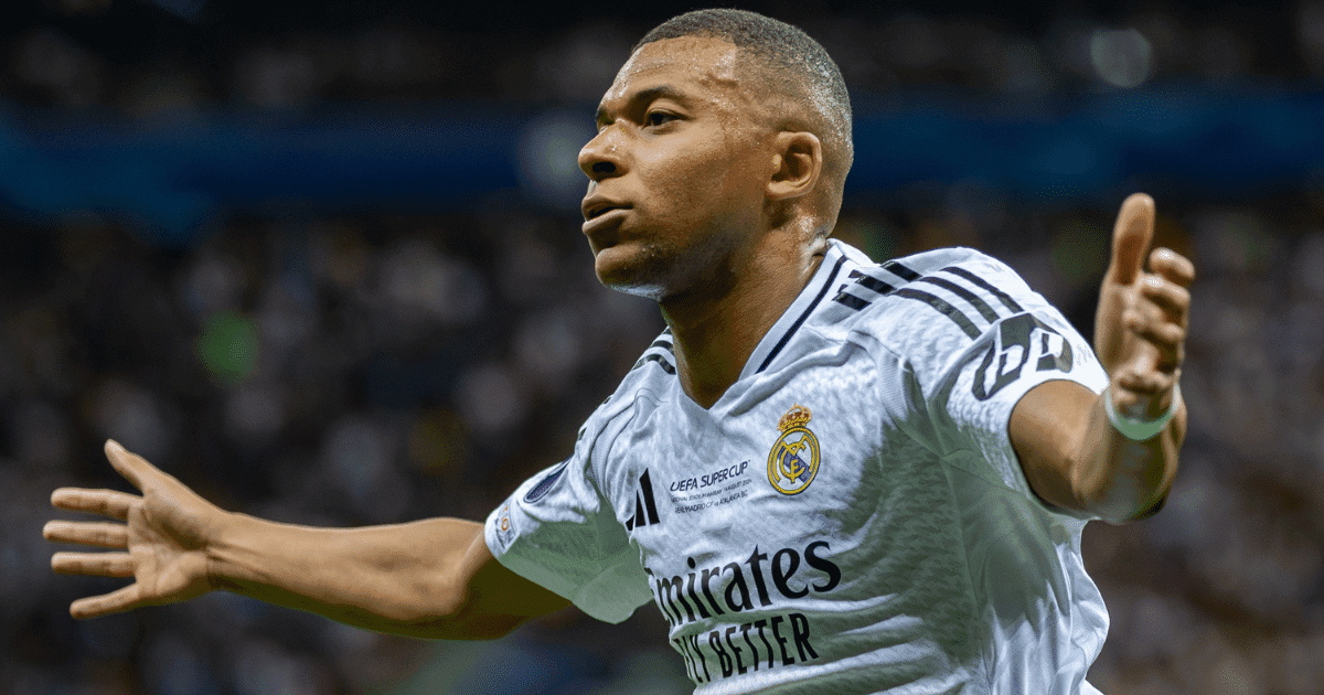 Fodboldspiller i hvid Real Madrid-trøje breder armene ud i jubel